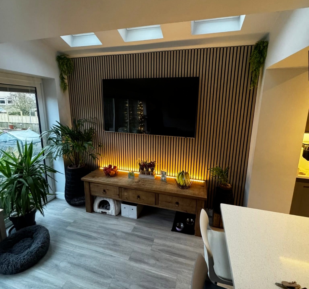 Modern acoustic slat wood media wall with vibrant LED strip lighting along a solid wood media unit